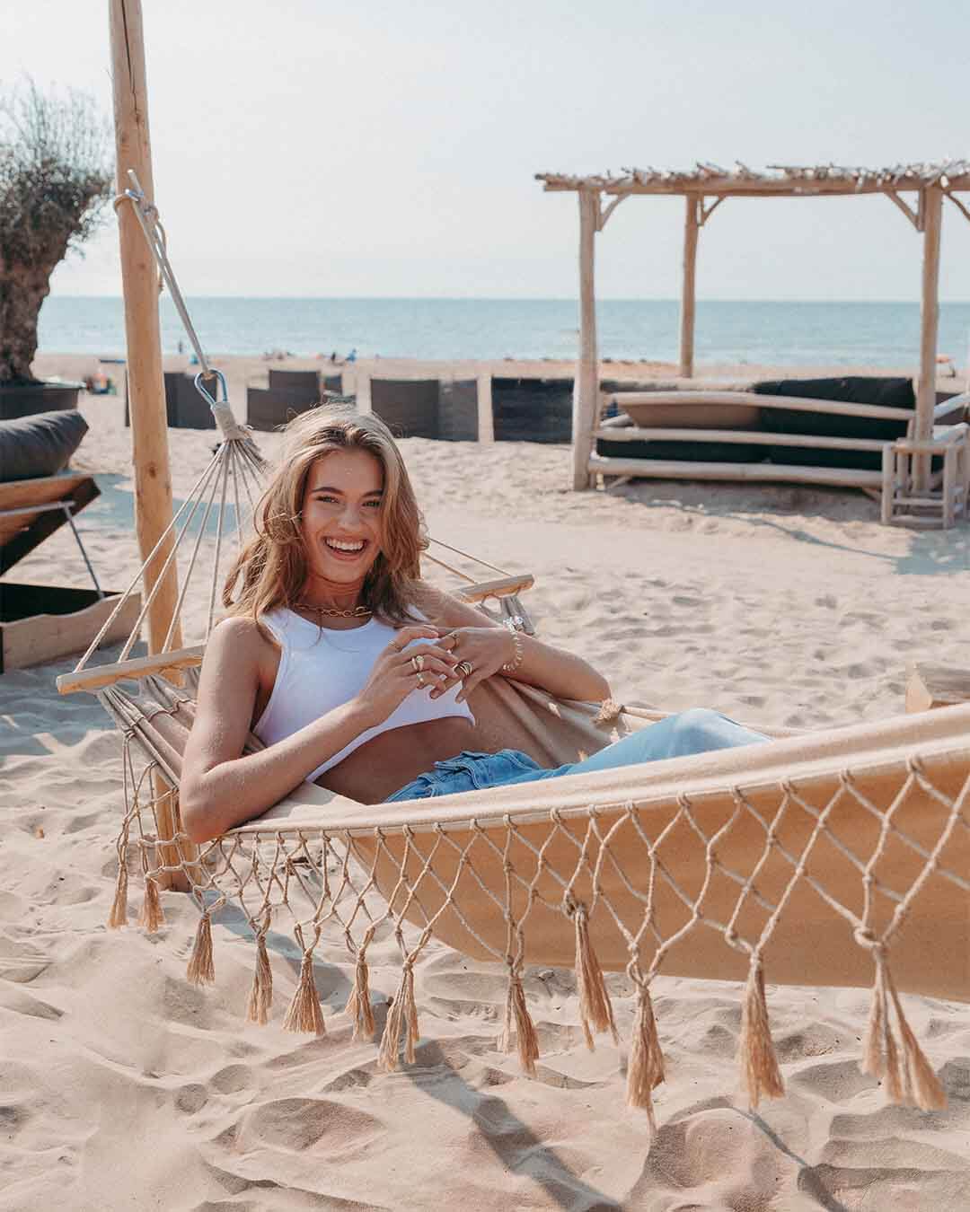 Lachend meisje in hangmat op het strand