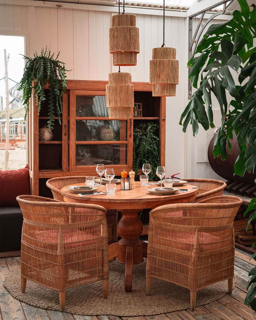 Ingedekte teakhouten tafel met grote kast bij hotspot Ubuntu in Zandvoort