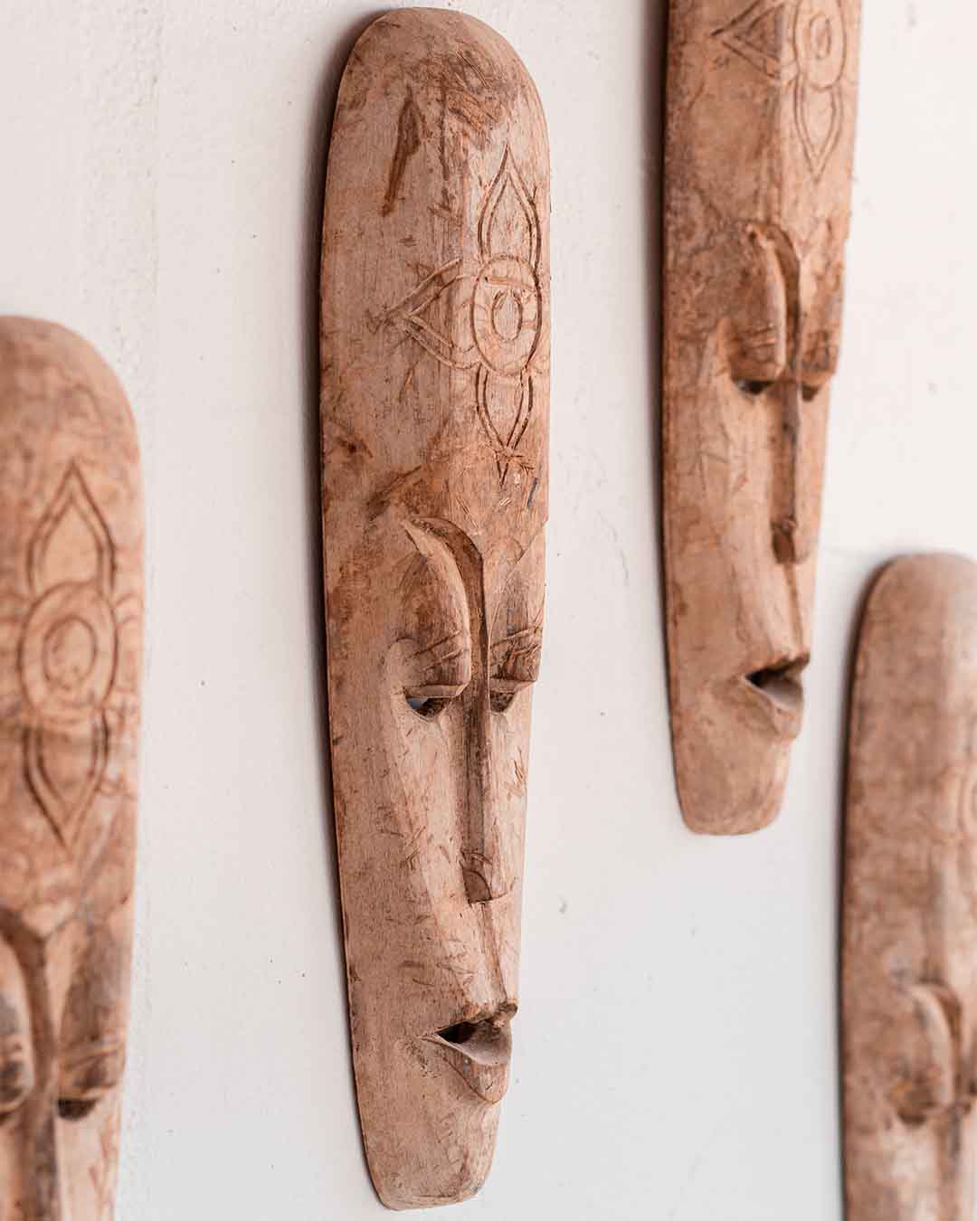 Detailshot van diverse houten maskers als wanddecoratie