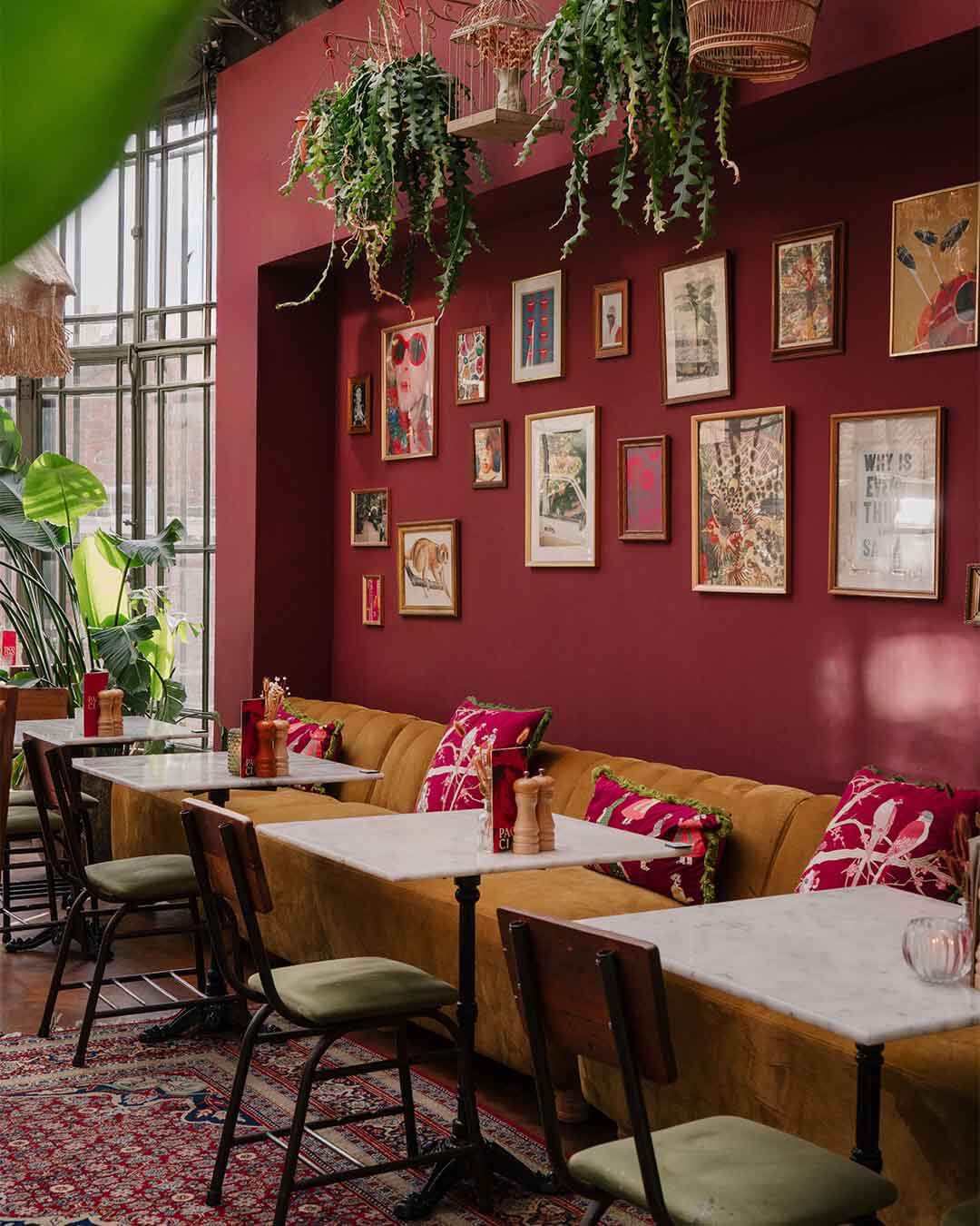 Bank onder muur vol met ingelijste prints bij hotspot Paco Ciao in Leiden