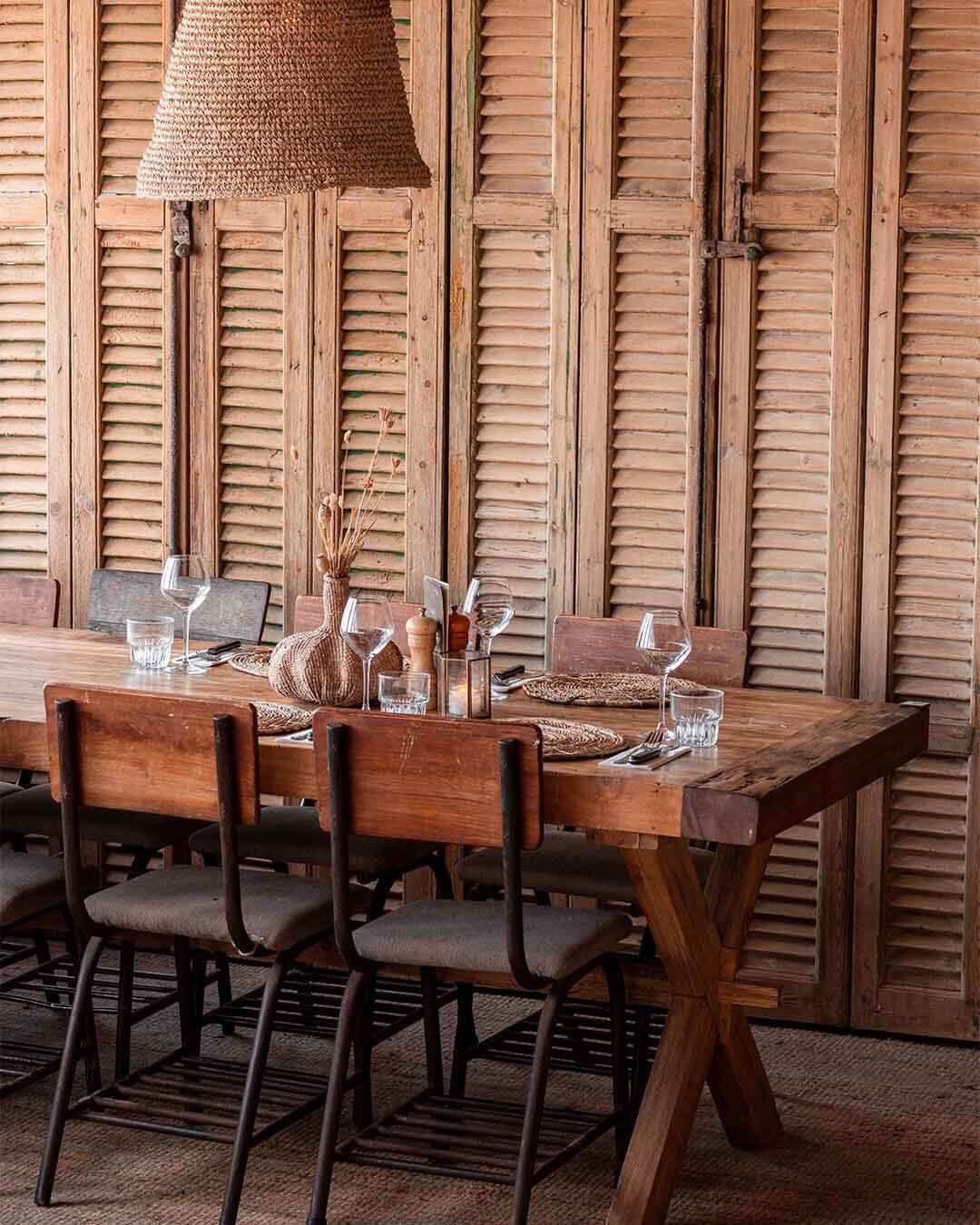 Interieurshot van ingedekte teakhouten tafel met rotan stoelen bij Kayuca