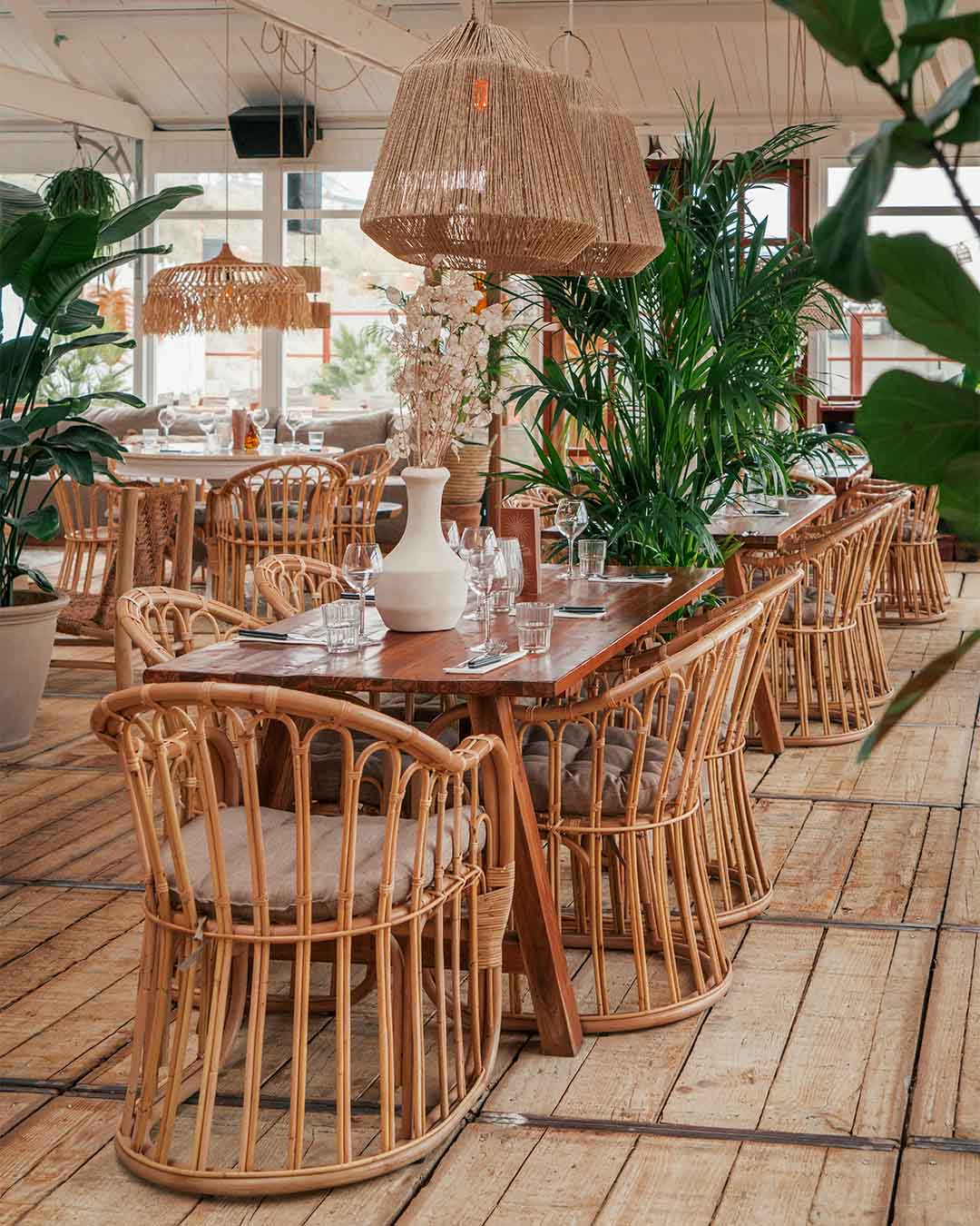 Ingedekte teakhouten tafel met veel planten bij hotspot Hippie Fish in Zandvoort