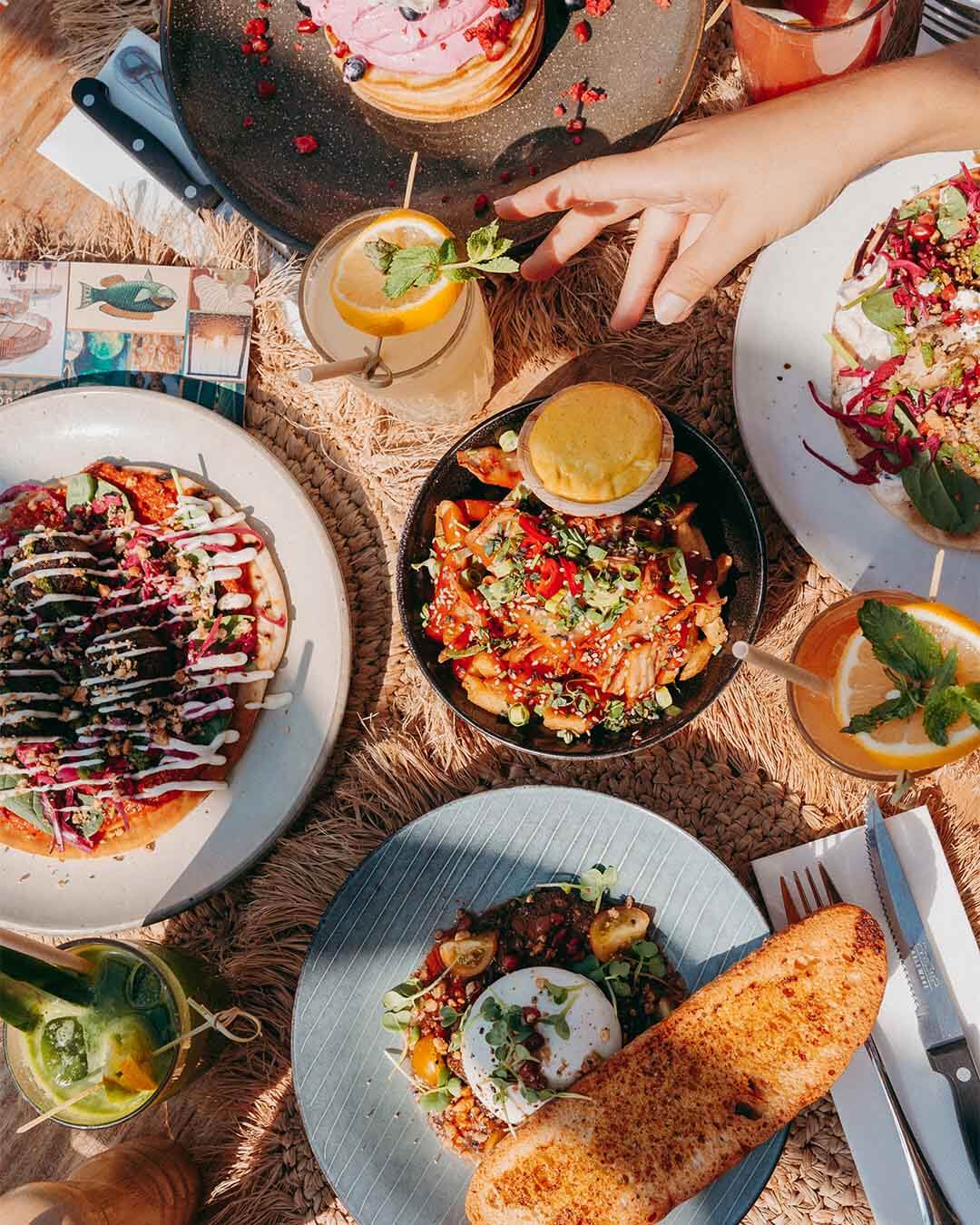 Bovenaanzicht van pita falafel, burrata met tomaat en loaded fries